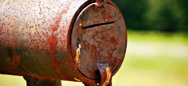 rusty round metal mailbox
